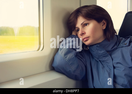 Young woman is traveling by train, looking to the window Stock Photo