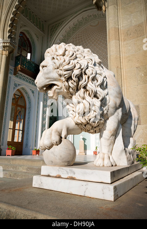 Sculpture of lion with a ball on a background of palace Stock Photo