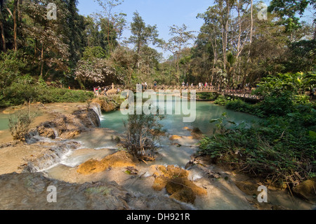 Horizontal view of tourists taking photographs from the bridge across the picturesque Kuang Si Falls in Laos. Stock Photo