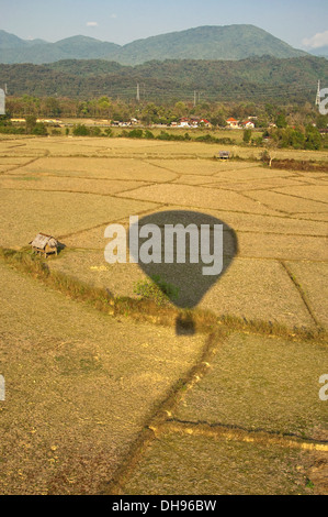 Vertical view of the countryside surrounding Vang Vieng from a hot air balloon, it's shadow on the ground. Stock Photo