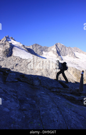 Silhouette of mountain walker with backpack and walking poles in mountains of the Wildgerlostal, Zillertal Alps, Tyrol, Austria Stock Photo