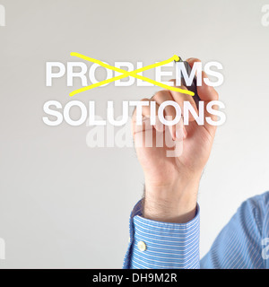 Solutions, not problems. Businessman crosses out problems for solutions with yellow marker pen on the screen Stock Photo