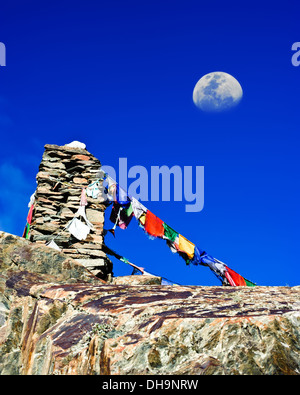 Buddhist stone tower praying flags and moon at Himalaya high mountain road pass at Manali - Leh highway over blue sky India Stock Photo