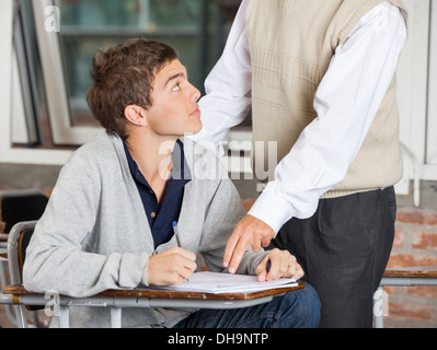 Teacher Explaining Test To Student In Classroom Stock Photo