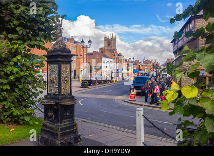 A view of Ludlow's 900 year old market with a ornamental disused water point framing the view across the colourful square Stock Photo