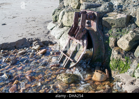 Surface water outfall with cast iron circular flap valve Beadnell, Northumberland, England, UK Stock Photo