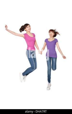 Two young women jumping in midair together on white background,smiling Stock Photo