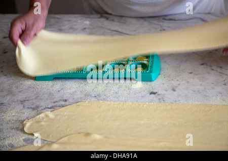 Woman Preparing Pasta Dough And Placing Over Ravioli Tray Stock Photo