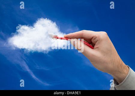 Cloud computing concept. Hand with ethernet cable connecting into cloud. Stock Photo