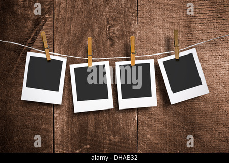 four photo paper attach to rope with clothes pins on wooden background Stock Photo