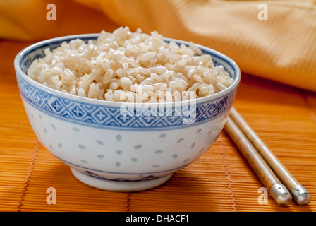 Brown rice in a blue and white Chinese bowl with chopsticks. Stock Photo