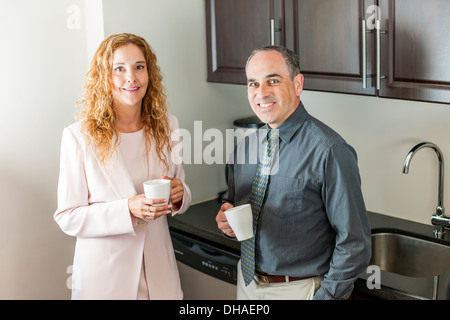 Two office coworkers on coffee break standing in kitchen Stock Photo