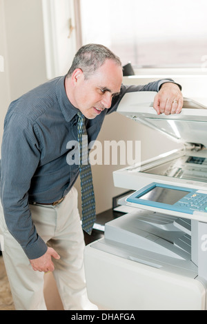 Frustrated business man opening photocopy machine in office trying to fix problem Stock Photo