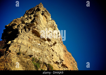 A jagged, pointed cliff against a deep blue sky. Stock Photo