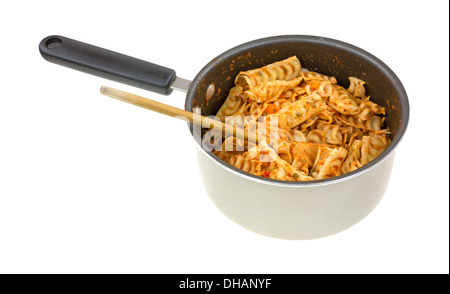 Home made pasta with a tomato sauce in a small saucepan with a wooden spoon on a white background. Stock Photo
