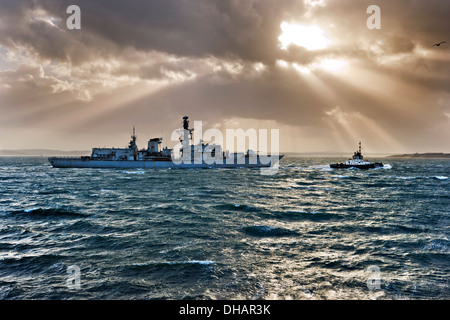 HMS Iron Duke, F234, of the Royal Navy being towed through The Solent by a tug into Portsmouth Harbour naval base, Hampshire, UK. Stock Photo