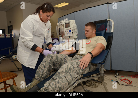 Kay Arroyo with the American Red Cross removes the tubes from the arm of U.S. Air Force Staff Sgt. Tyler Kellogg during the on-base blood drive at McEntire Joint National Guard Base of the South Carolina Air National Guard, Nov. 3, 2013. Kellogg, a fire t Stock Photo