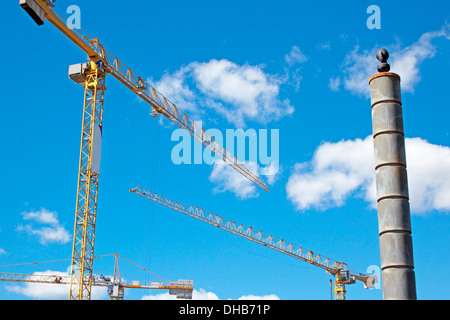 three yellow tower cranes against a clouded skyline Stock Photo