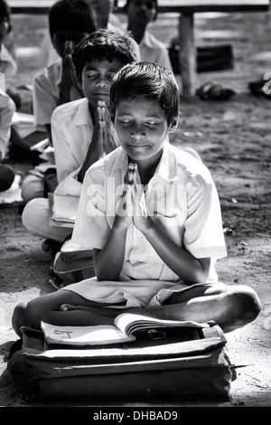 Rural Indian village high school boys doing morning prayers in an outside class. Andhra Pradesh, India. Monochrome Stock Photo