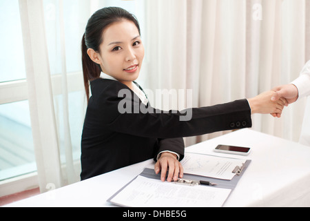 Businesswomen shaking hands in an office Stock Photo
