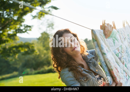 A woman hanging laundry on the washing line, in the fresh air. Stock Photo