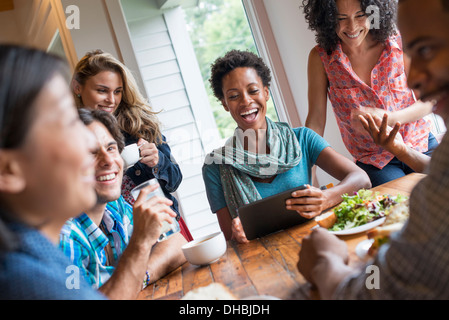 A group of people meeting in a cafe. Using digital tablets and smart phones. Having a meal together. Stock Photo