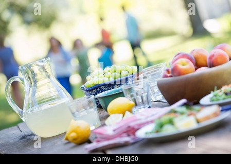 A summer buffet of fruits and vegetables, laid out on a table. People in the background. Stock Photo