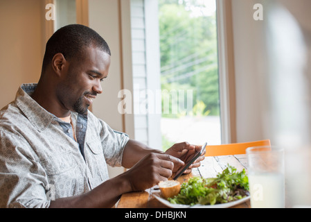 A man sitting in a cafe with a cup of coffee, using a smart phone. Stock Photo