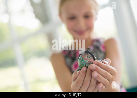 A young girl holding out a small globe in the palms of her cupped hands. Stock Photo
