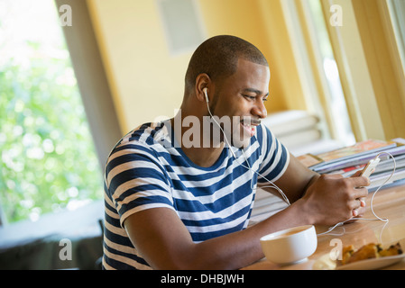 A man sitting in a cafe, having a cup of coffee, listening to music with headphones. Stock Photo