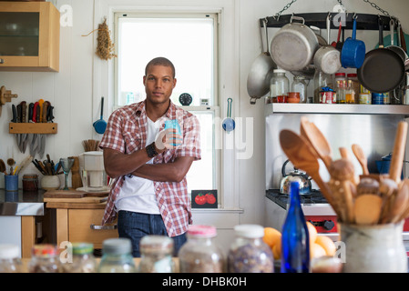 A man holding a drink standing in a farmhouse kitchen. Stock Photo