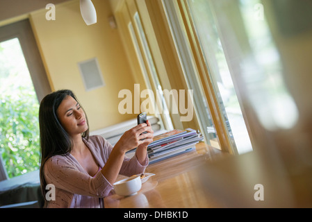 A woman having a cup of coffee and using a smart phone. Stock Photo