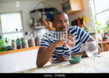 A man sitting at a table eating dessert, holding a glass of wine. Stock Photo