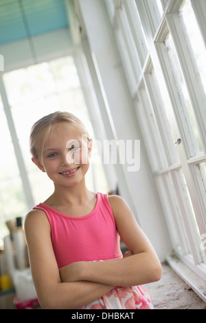 A young girl in a kitchen wearing a pink dress. Stock Photo