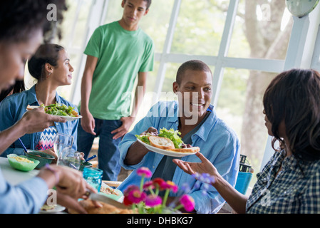 A group of women and men around a table sharing a meal in a farmhouse kitchen. Stock Photo
