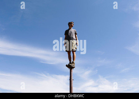 Man standing balancing on metal post looking towards expansive sky Surprise Mountain Alpine Lakes Wilderness Mt Stock Photo