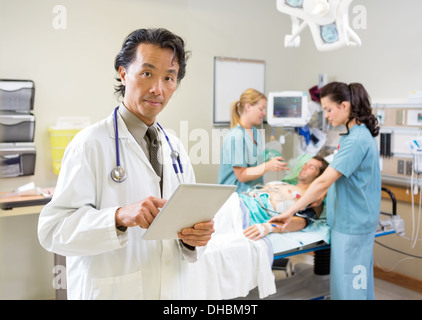 Doctor Using Digital Tablet While Nurses Treating Patient Stock Photo