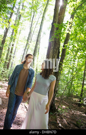 Two people, a young woman and man, walking side by side in the woods. Stock Photo