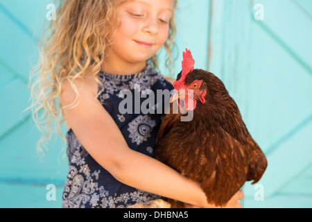 A young girl holding a chicken in her arms. Stock Photo
