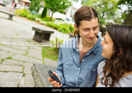 A young couple side by side, flirting and taking photographs.