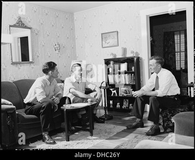 Harry Fain, a coal loader at Inland Steel Company, is seen conversing with friends during a Sunday morning visit. The image reflects the industrial labor of the time in Wheelwright. Stock Photo