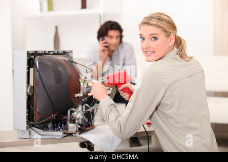 Woman repairing television with soldering iron Stock Photo