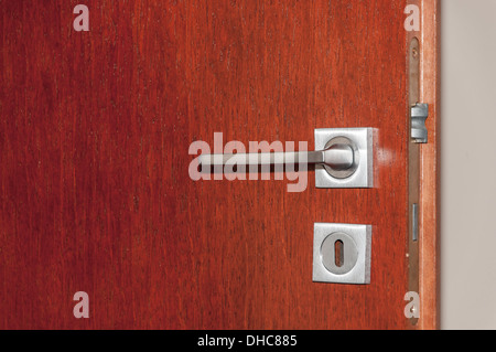 Modern style door handle on natural wooden door Stock Photo