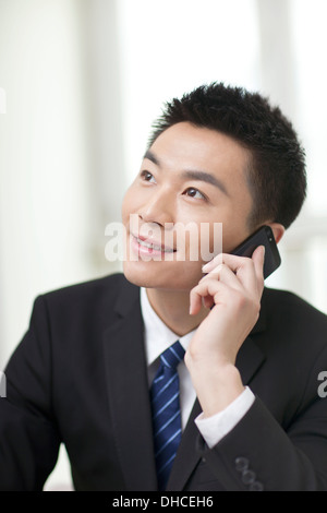 Portrait of businessman sitting at desk and using cell phone Stock Photo