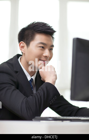 Portrait of businessman sitting at desk,looking at computer,close-up Stock Photo