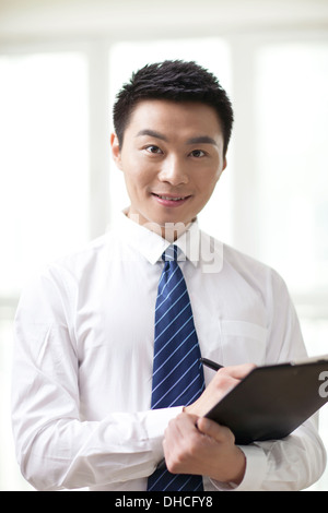 Portrait of young businessman looking and signing documents Stock Photo