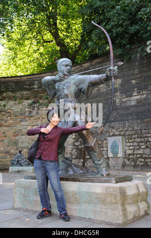 Japanese tourist posing beside Robin Hood statue, Nottingham, England, UK Stock Photo