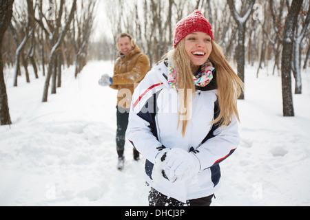 Portrait of happy girl in winterwear laughing on background of her boyfriend outside Stock Photo