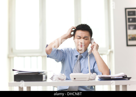 Portrait of young businessman talking on phone in office Stock Photo