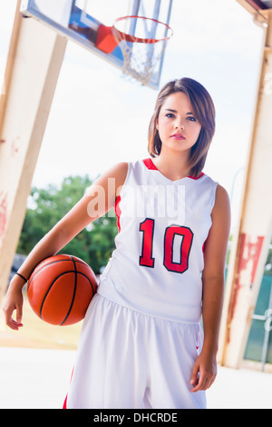 USA, Texas, American High School Girl in Sports Team Outfit with Basketball Stock Photo